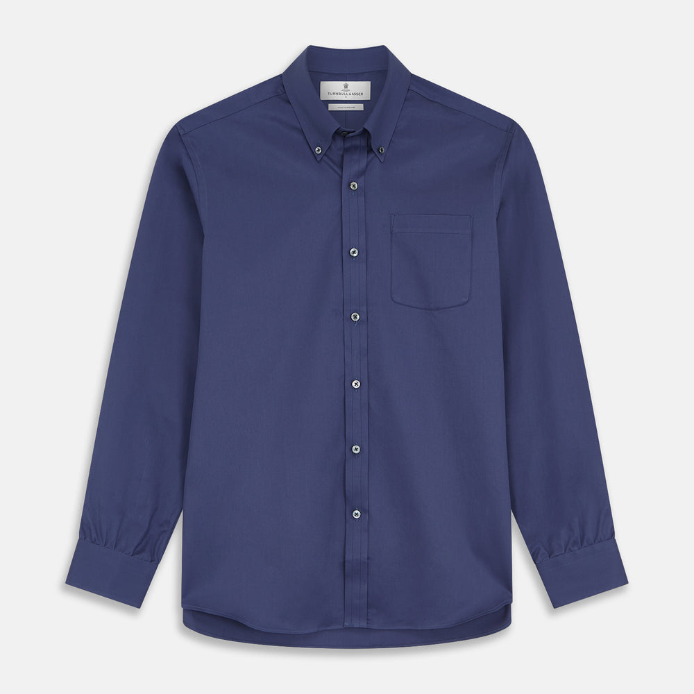 The Blue Piece Dyed Weekend Fit Suffolk Shirt by Turnbull & Asser features a button-down Dorset collar, chest pocket, white buttons, and long sleeves in classic navy, laid flat against a white background.