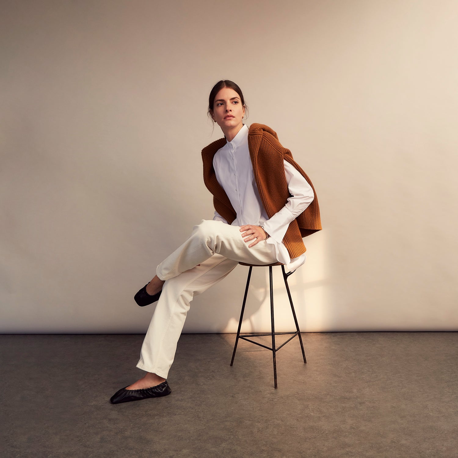 View 9 of product A person with curly hair wears the Turnbull and The Deck White Cotton Minimalist Shirt by Turnbull & Asser, paired with pants. Posed against a plain background, their minimalist silhouette is highlighted in this black and white image.