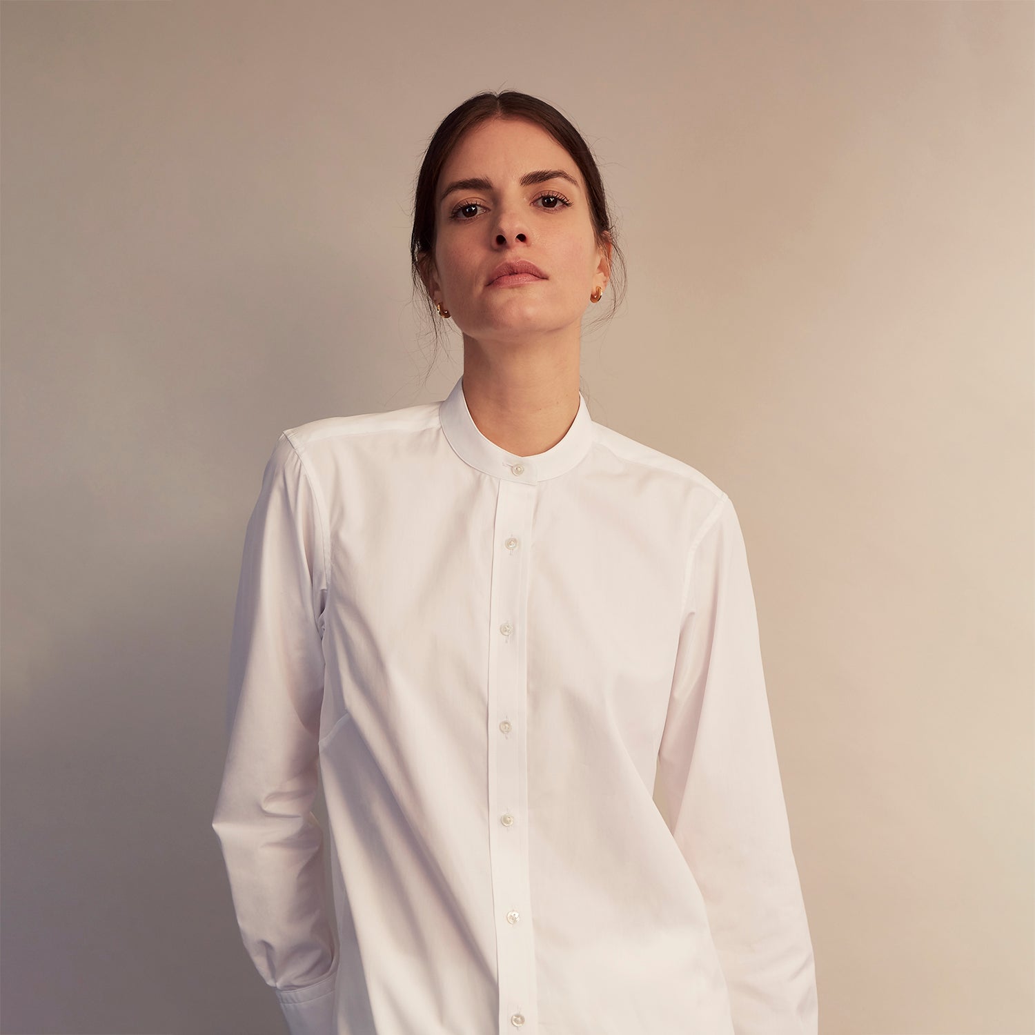 View 5 of product The White Cotton Lauren Shirt by Turnbull & Asser, featuring a stand collar, button-down front, and elongated body, is laid flat on a plain white background.