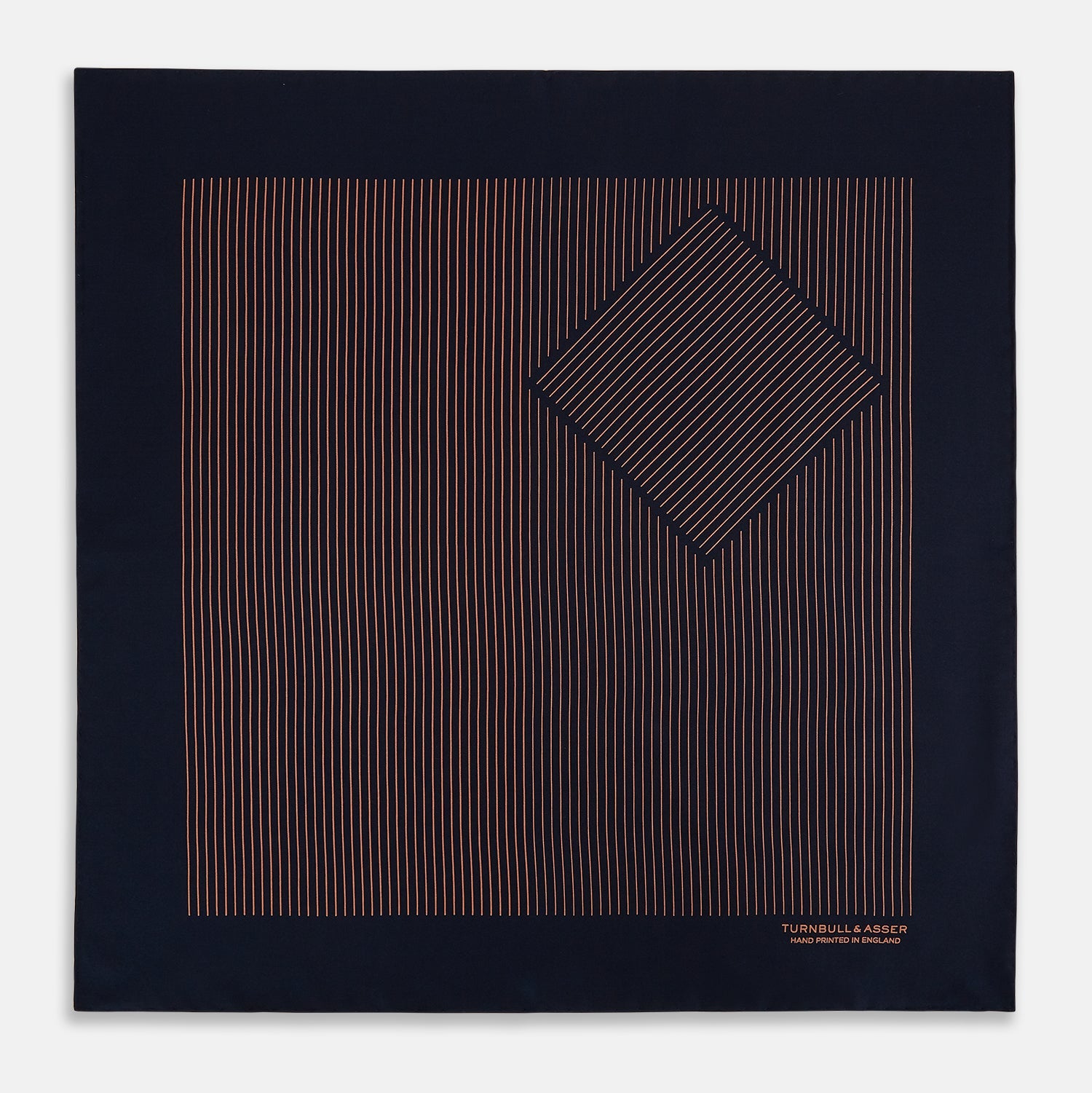 View 3 of product The Turnbull & Asser Navy and Blush Stripe Silk Pocket Square features thin blush stripes on navy silk, finished with "TURNBULL & ASSER HAND PRINTED IN ENGLAND" in the corner, highlighting its refined English craftsmanship.