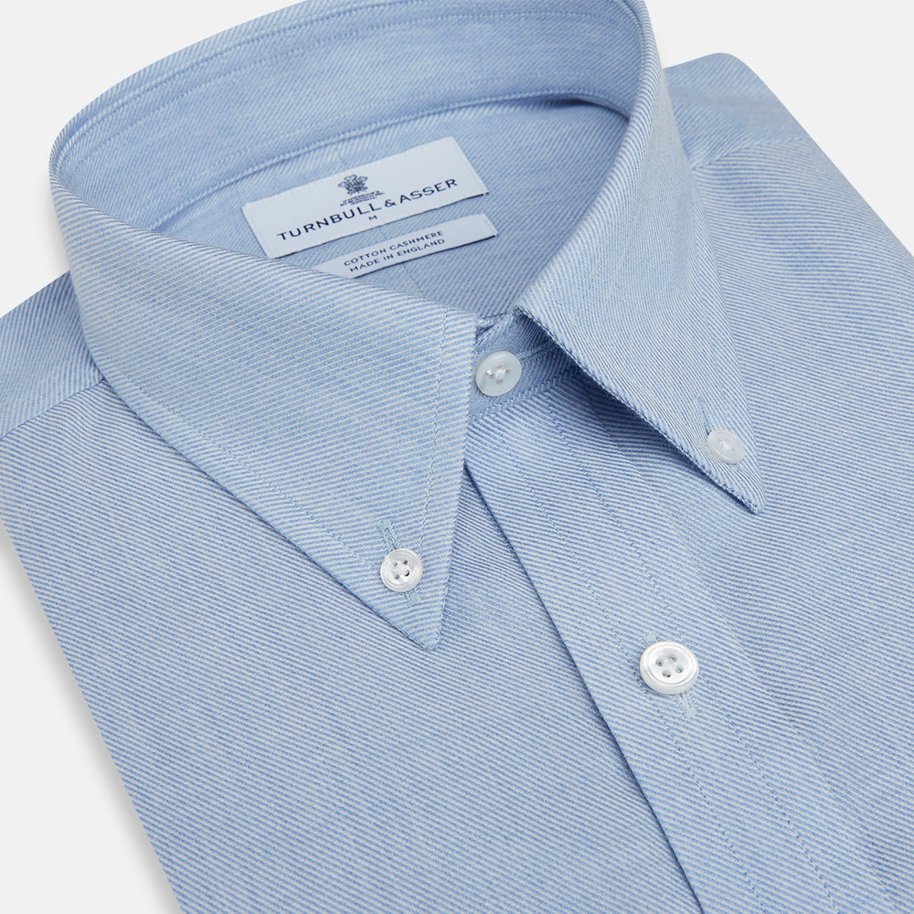 The Turnbull & Asser Pale Blue Cotton Cashmere Dorset Collar Richmond Shirt features long sleeves, a button-down collar, white buttons, and a chest pocket. It is neatly displayed flat on a white background.