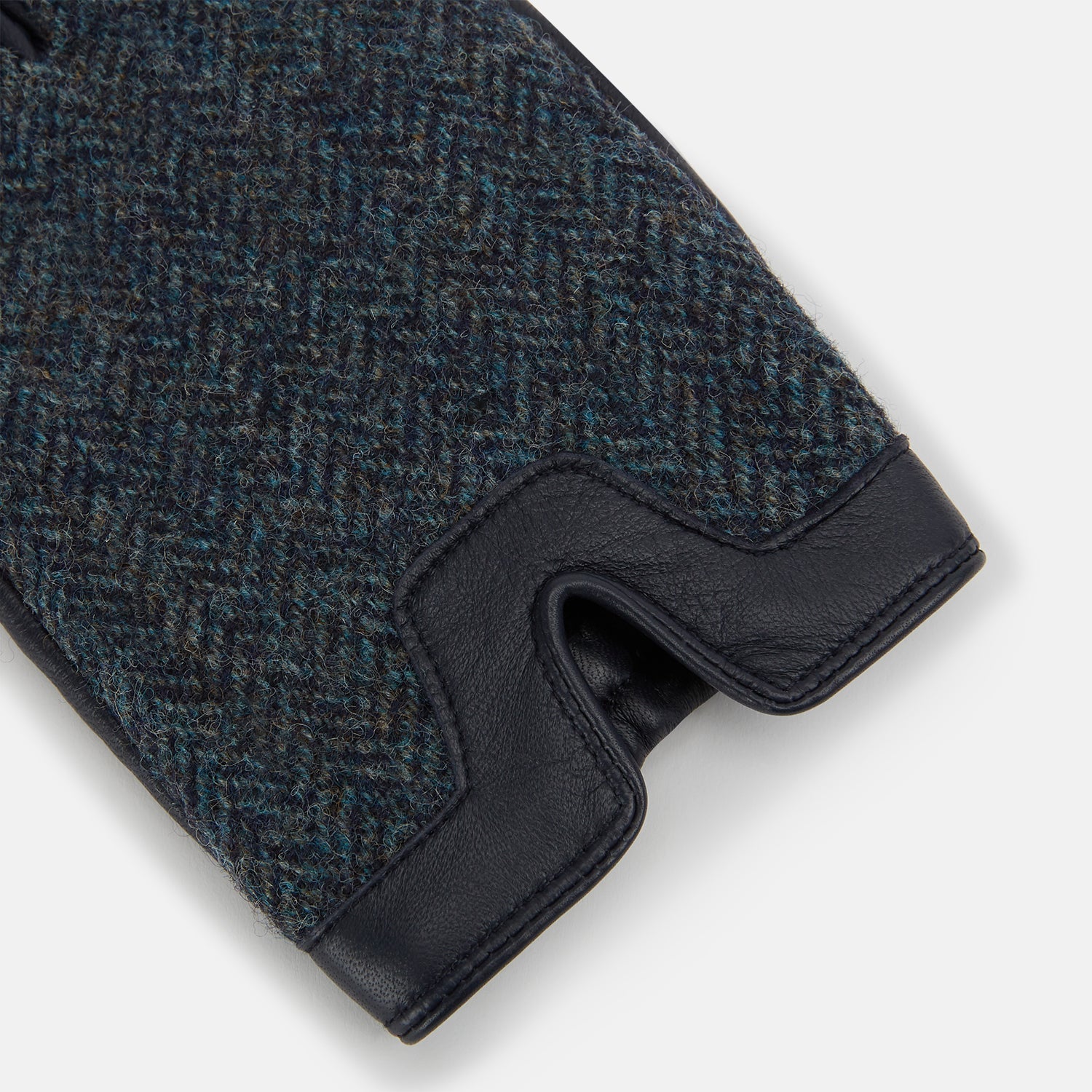 View 2 of product Turnbull & Asser Navy Herringbone Tweed Cashmere-Lined Leather Gloves are shown on a white background: one glove features dark navy herringbone tweed, the other shows a smooth black leather palm.