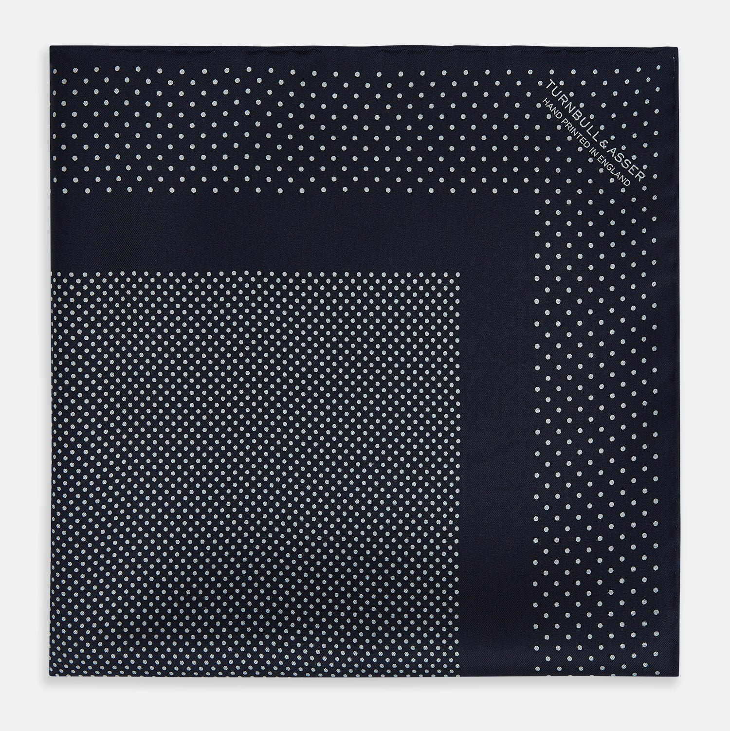View 3 of product The Turnbull & Asser Navy and Grey Dot Silk Pocket Square features a neatly folded design with small grey dots on navy silk and a solid border, showcasing both sides of the luxurious fabric.