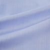 View 6 of product The Turnbull & Asser BLUE HERRINGBONE TAILORED FIT SHIRT WITH KENT COLLAR features long sleeves and buttoned cuffs, offering a timeless formal look in a classic light blue herringbone fabric, laid flat on a white background.