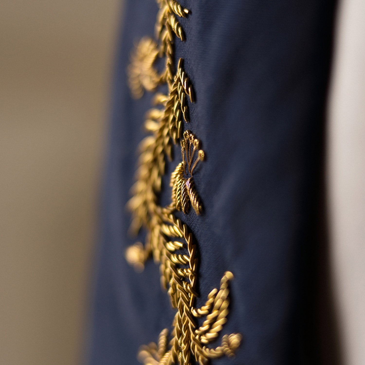 View 5 of product The Turnbull & Asser Navy Gold Embroidered Botanical Tie features intricate gold botanical embroidery on navy blue silk, neatly rolled with the detailed tip facing forward.