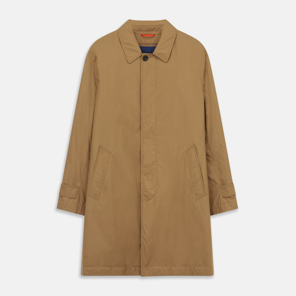 A person wears the Turnbull & Asser Camel Quintern Sealup Raincoat with Detachable Liner, paired with dark pants, standing against a plain light gray background, showing the sleek technical rainwear style with one hand in a pocket.