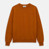 View 1 of product The Turnbull & Asser Rust Glenn Crew Neck Jumper is a plain, long-sleeved Scottish knitwear piece with ribbed cuffs and hem, shown laid flat on a white background.