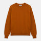 The Turnbull & Asser Rust Glenn Crew Neck Jumper is a plain, long-sleeved Scottish knitwear piece with ribbed cuffs and hem, shown laid flat on a white background.