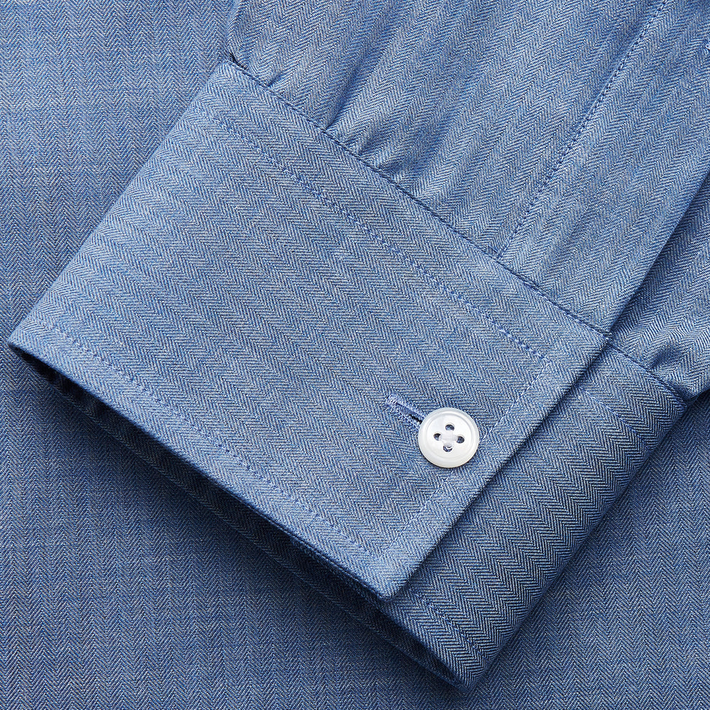 The Turnbull & Asser Blue Cotton Weekend Fit Blake Shirt features a light blue color, long sleeves, stand collar, white buttons, and a curved hem—ideal for casual weekends. Laid flat on a white background.
