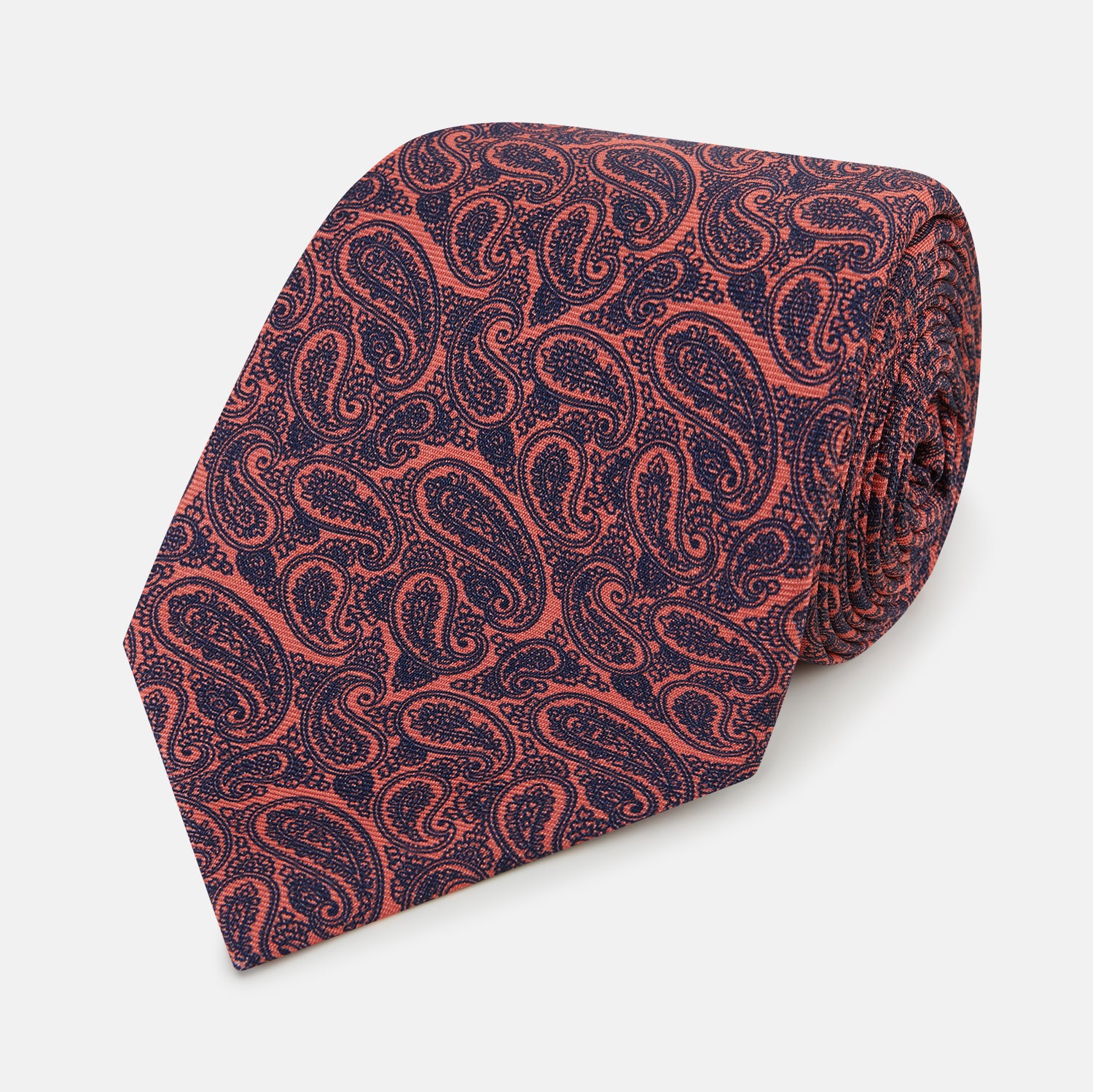 View 1 of product A rolled-up Turnbull & Asser Orange Paisley Silk Tie, featuring an elegant pattern, is displayed against a plain white background.