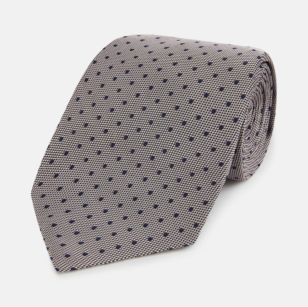The Turnbull & Asser Navy and Lilac Micro Dot Silk Tie is shown rolled up on a white background, featuring a refined pattern of small lilac dots on navy silk.