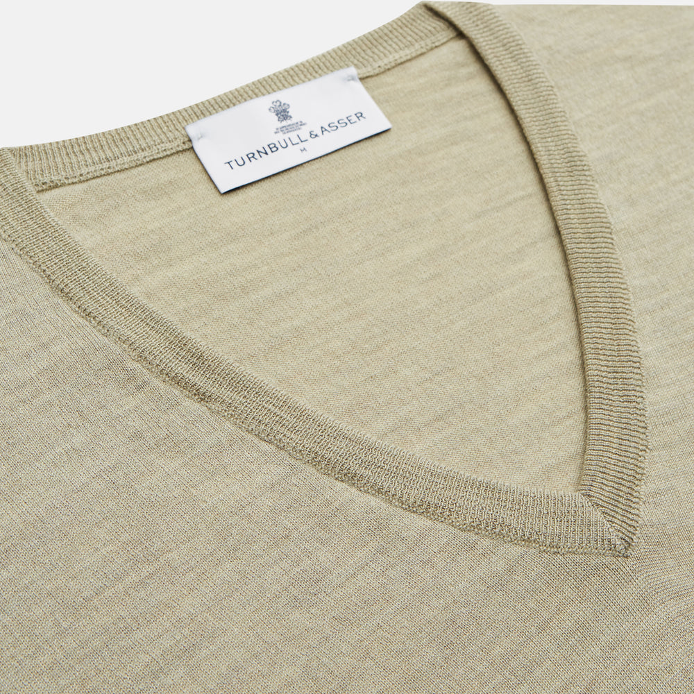 A light green Kennedy Merino V-neck jumper by Turnbull & Asser is laid flat on a white background. This knitwear piece features ribbed cuffs and hem, offering a simple, classic design ideal for any wardrobe.