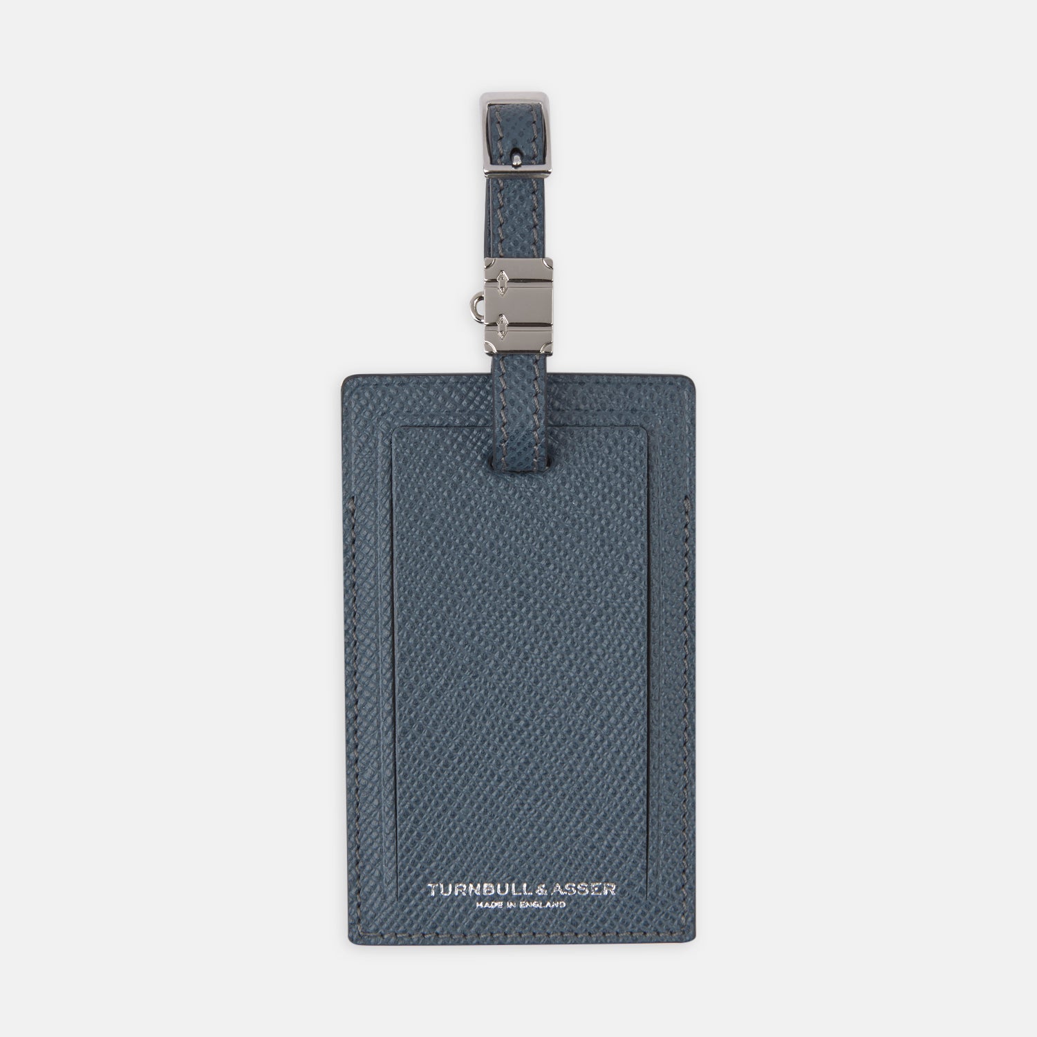 View 1 of product The Blue Leather Luggage Tag by Turnbull & Asser features textured leather, a metal buckle and strap, and displays the logo with "Made in England" printed in white at the bottom.