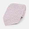 View 1 of product The Turnbull & Asser Lilac Flower Patterned Silk Tie features a light pink hue with a repeating white floral motif, shown rolled up on a plain white background.