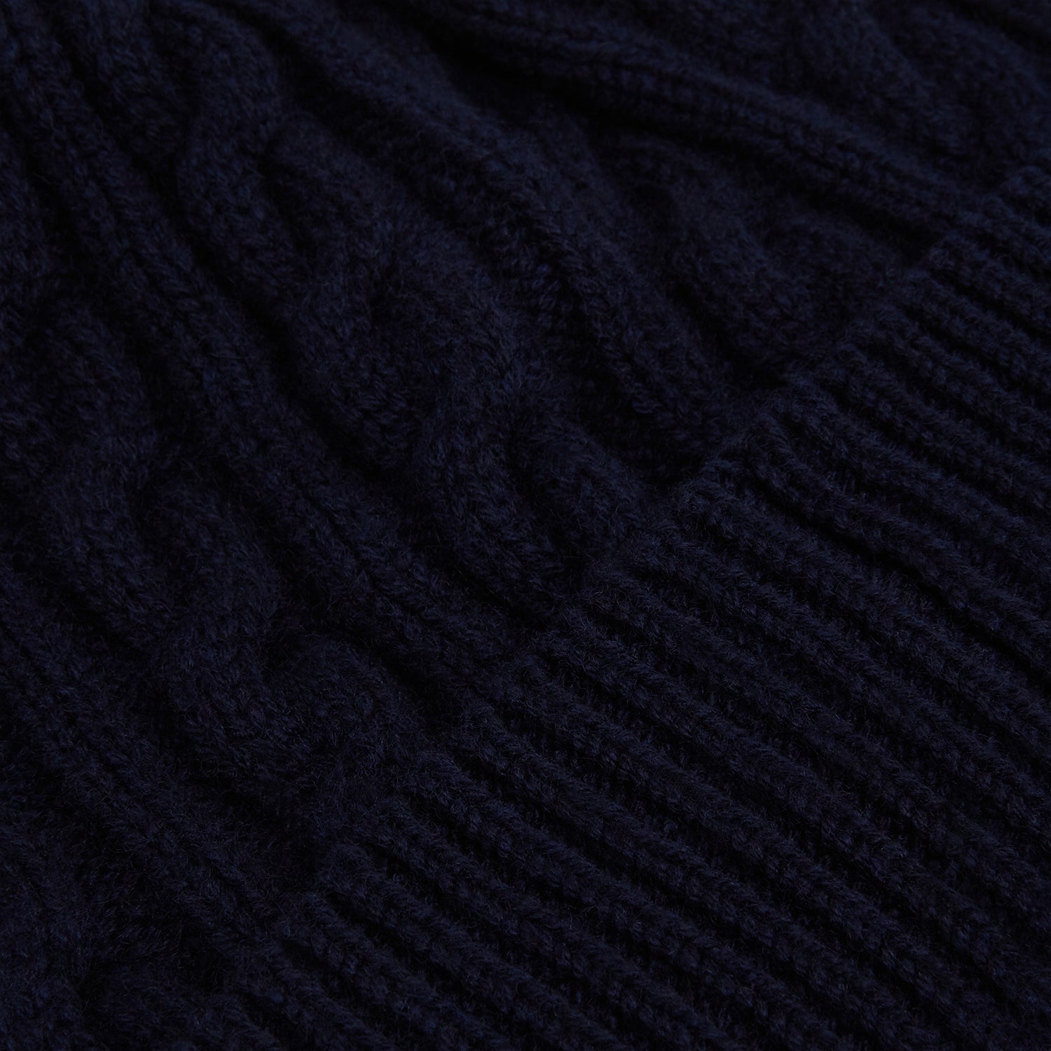 View 2 of product The Turnbull & Asser Midnight Blue Cable Knit Cashmere Beanie features a ribbed folded brim and chunky cable pattern, expertly knitted in England, and shown against a plain white background.