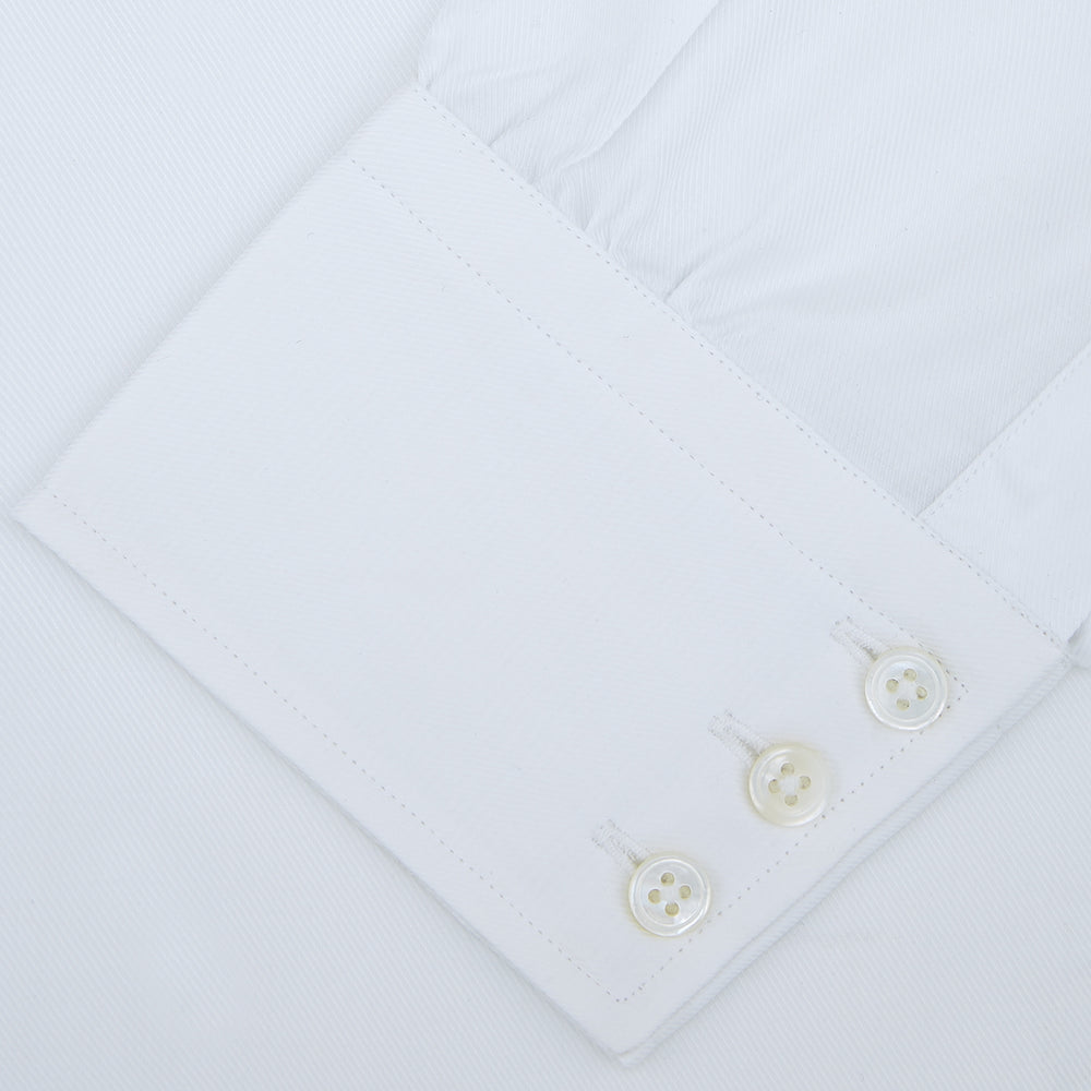 A neatly folded White Sea Island Quality Cotton Twill Shirt by Turnbull & Asser, featuring a T&A collar and 3-button cuffs, is displayed on a light grey background with a label visible inside the collar.