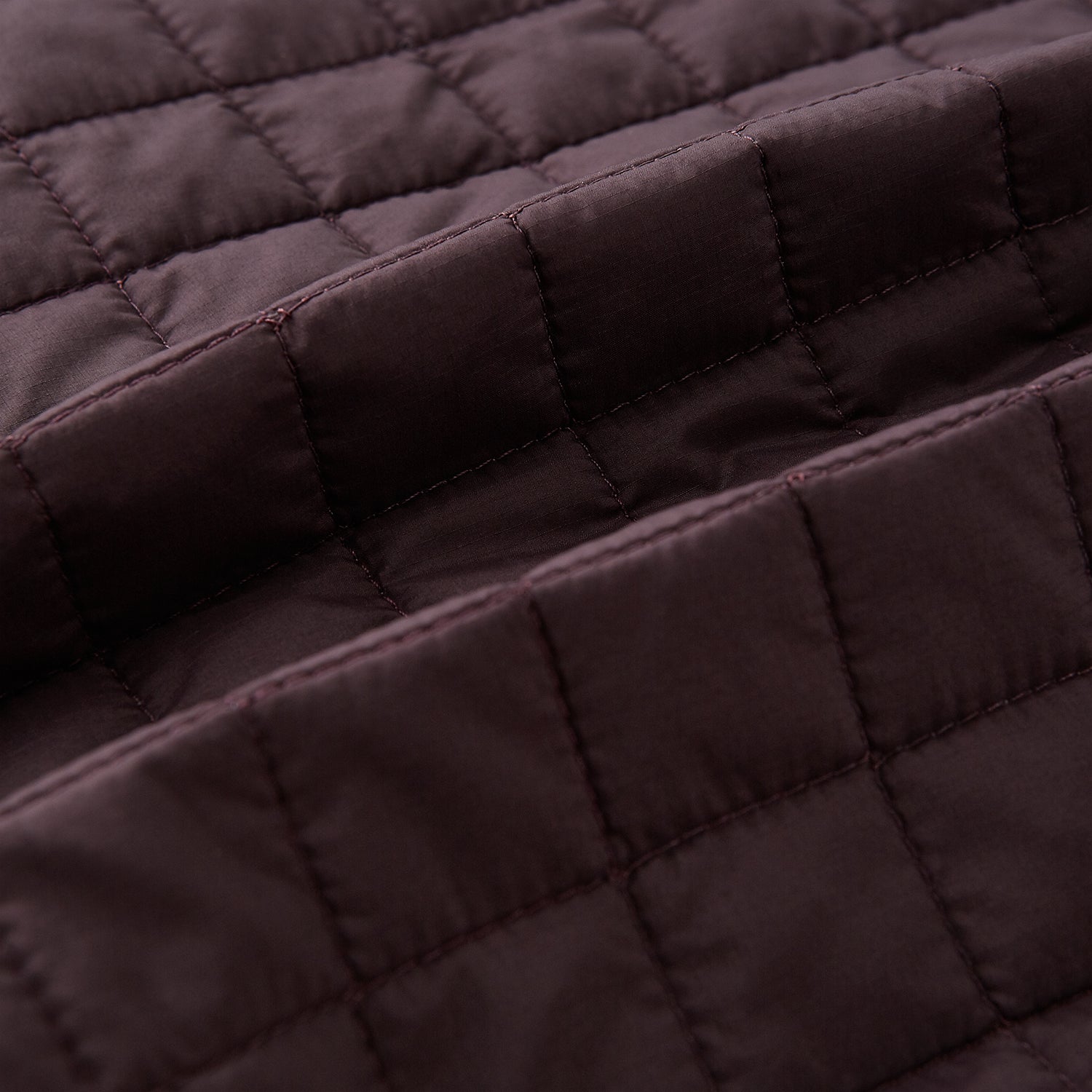 View 4 of product The Turnbull & Asser Burgundy Double-Breasted Quilted Gilet is a sleeveless vest with black buttons, an angled front, subtle check pattern, side and chest pockets—an ideal menswear piece for versatile layering.