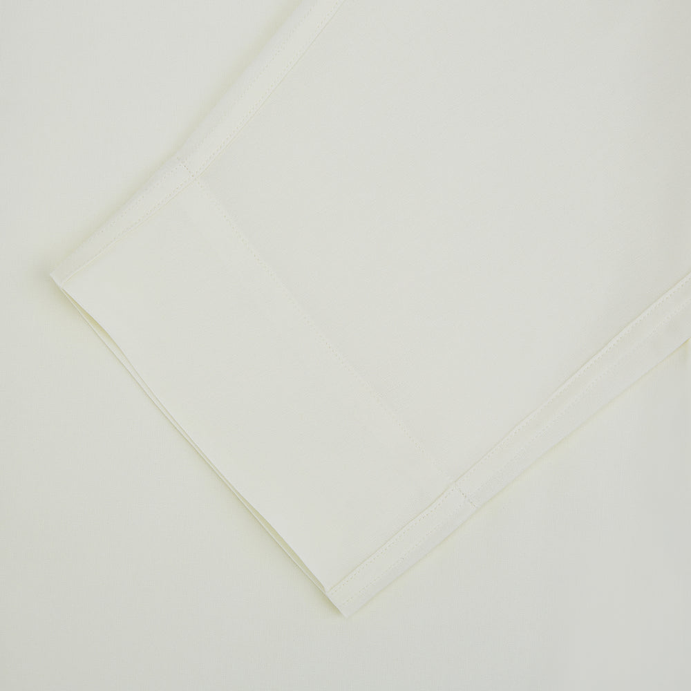 The Turnbull & Asser Cream Silk Pyjama Set, shown laid flat on a white background, features a long-sleeve button-up top with a chest pocket and matching pants with an elastic drawstring waist—ideal for comfortable loungewear.