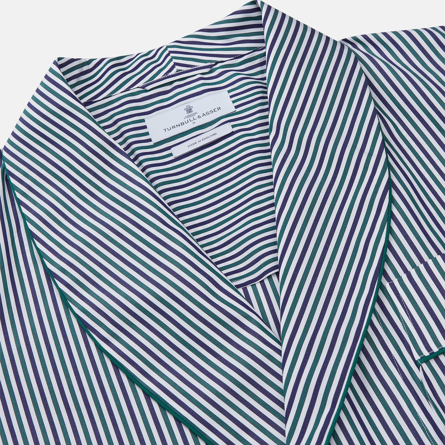 View 2 of product The Turnbull & Asser Green and Blue Stripe Cotton Arnold Gown features long sleeves, a knee-length cut, a shawl collar, front pockets, and an elegant wrap belt at the waist.