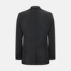 View 3 of product The Turnbull & Asser Graphite Knitted Oxford Blazer for men features a dark gray hue, two buttons, notched lapels, and three front pockets—a modern British-inspired piece styled elegantly against a light background.