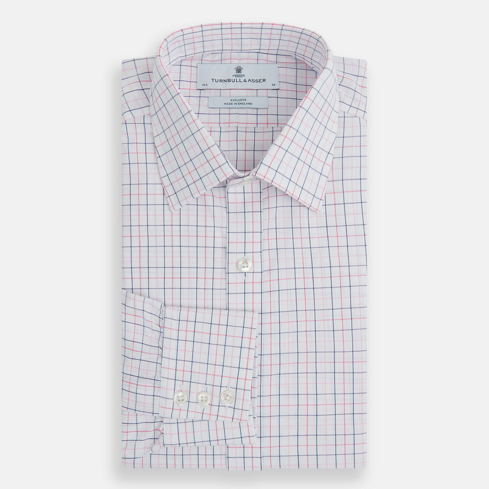 The Turnbull & Asser Pink Overlay Grid Check Mayfair Shirt is a long-sleeved, button-up with a collar and buttoned cuffs, featuring a white base and thin pink grid lines. Laid flat against a white surface.