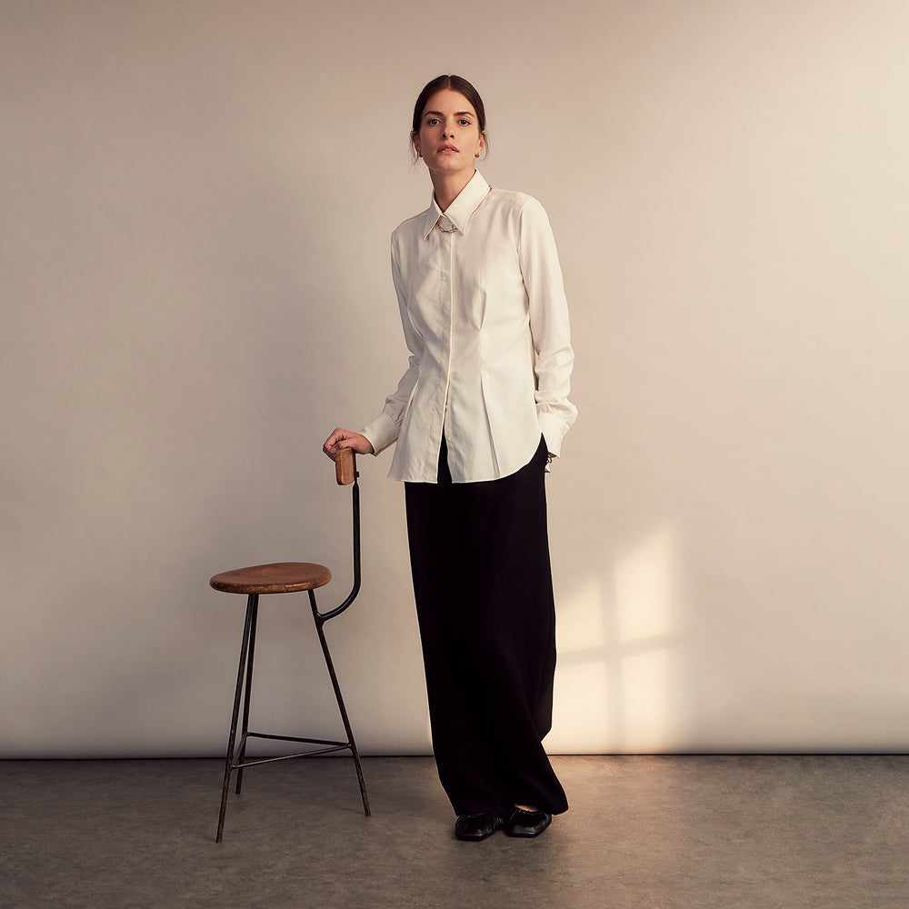 The Cream Silk Tailored Bianca Shirt by Turnbull & Asser features long sleeves, a pointed collar, and curved hem in soft-touch peace silk with a tailored fit. Shown laid flat on a white background.