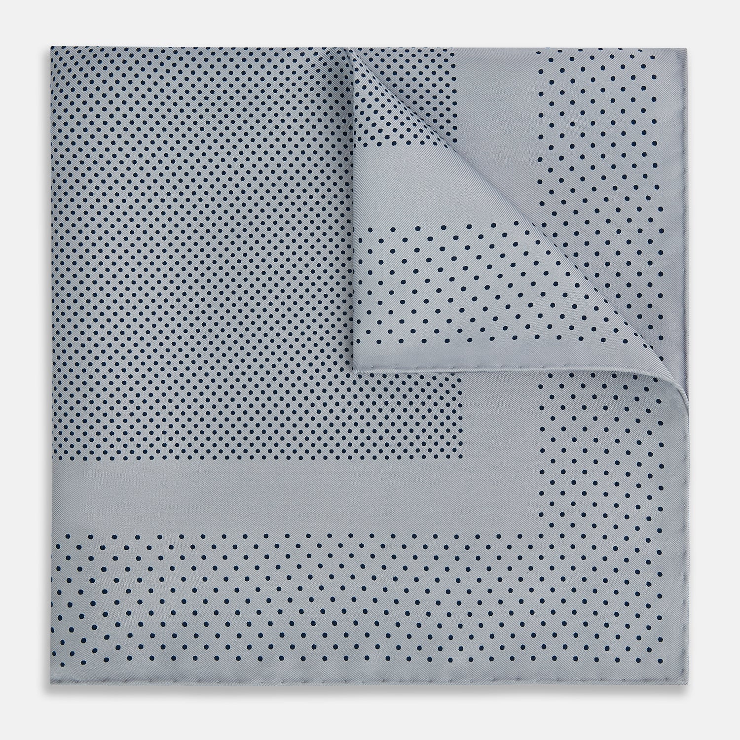 View 6 of product The Turnbull & Asser Grey Dot Silk Pocket Square features a light gray silk design with navy polka dots and a solid border. Elegantly handmade, it is shown with one corner folded to display both sides.