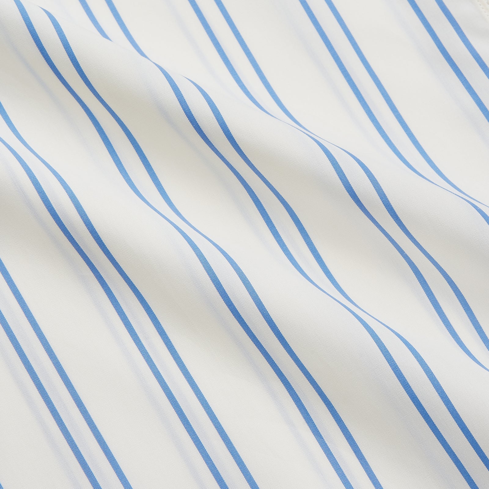 View 5 of product A man with short brown hair stands against a beige background in a Turnbull & Asser Blue and Off-White Stripe Cotton Weekend Fit Finch Shirt, featuring vertical stripes and a Derby collar, paired with dark pants. One hand is in his pocket; he has a neutral expression.