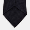 View 4 of product The GRENADINE NEW NAVY TIE by Turnbull & Asser features a dark navy blue woven texture, making it the perfect accessory for refined looks. Displayed against a plain white background.