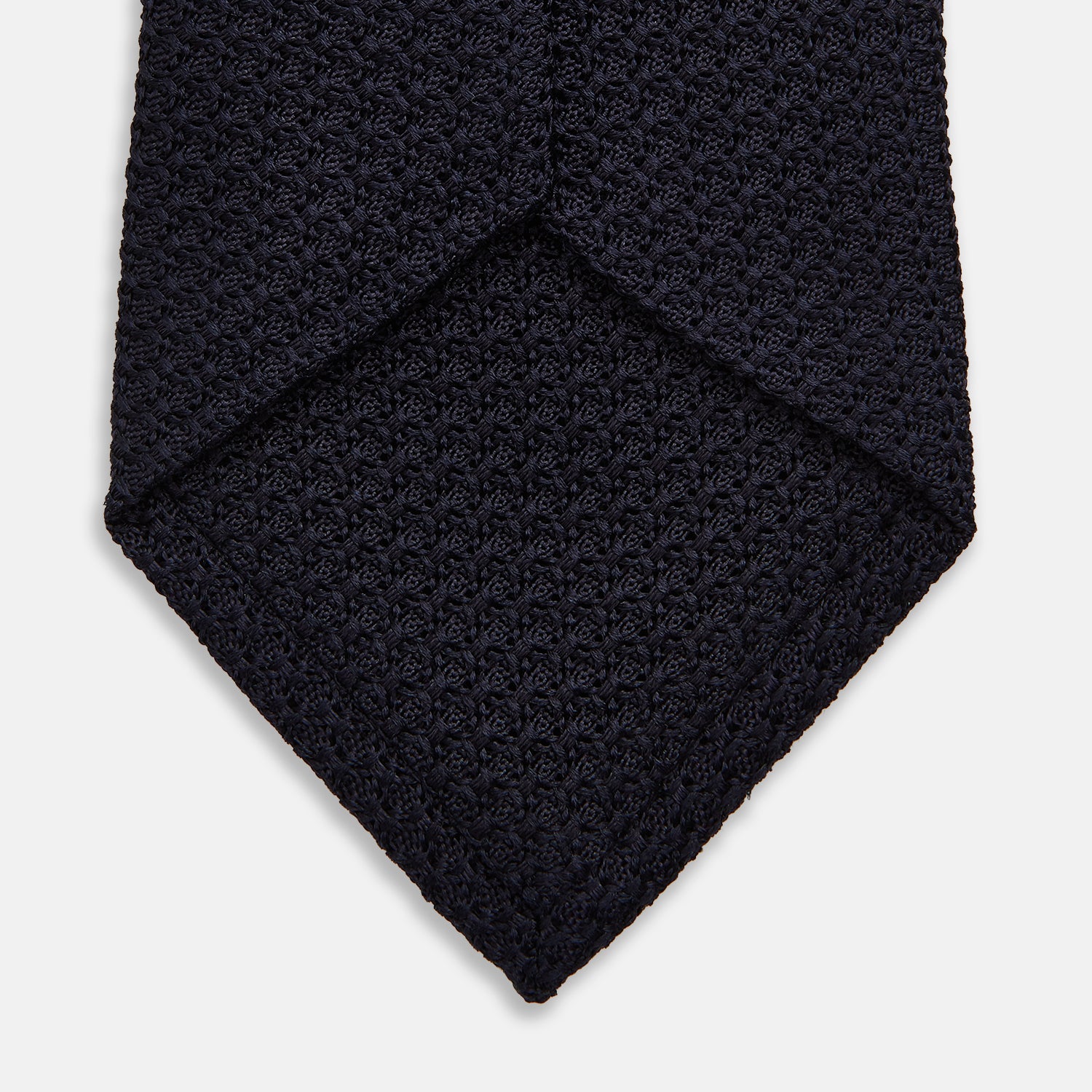 View 4 of product The GRENADINE NEW NAVY TIE by Turnbull & Asser features a dark navy blue woven texture, making it the perfect accessory for refined looks. Displayed against a plain white background.