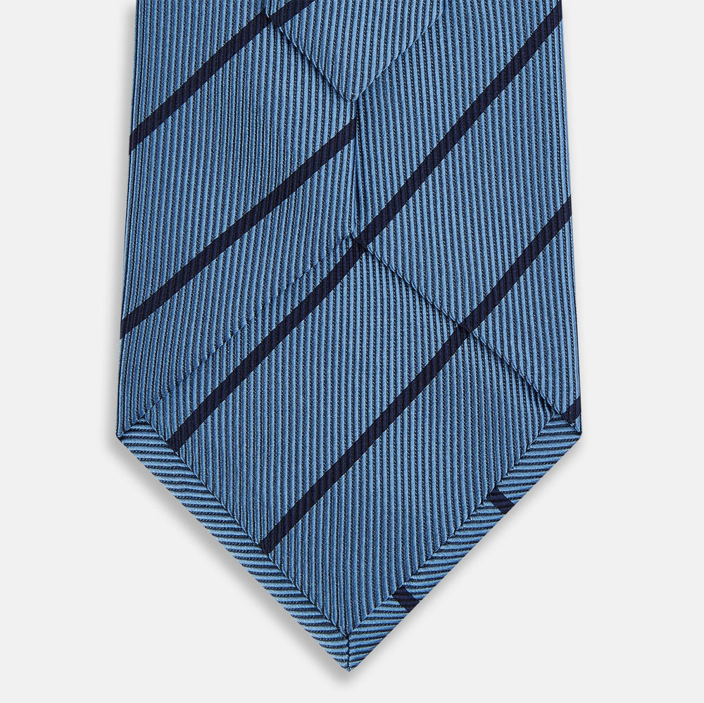 The Turnbull & Asser Blue and Navy Blazer Stripe Silk Tie features diagonal navy stripes and is shown rolled up against a plain white background.