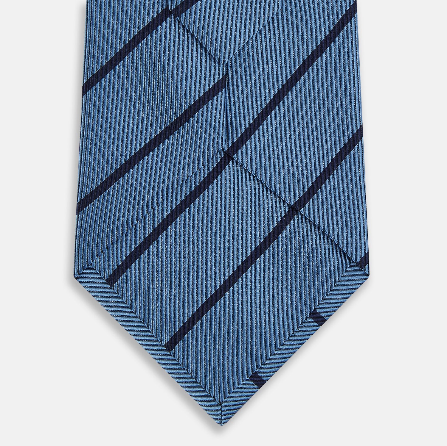 View 3 of product The Turnbull & Asser Blue and Navy Blazer Stripe Silk Tie features diagonal navy stripes and is shown rolled up against a plain white background.
