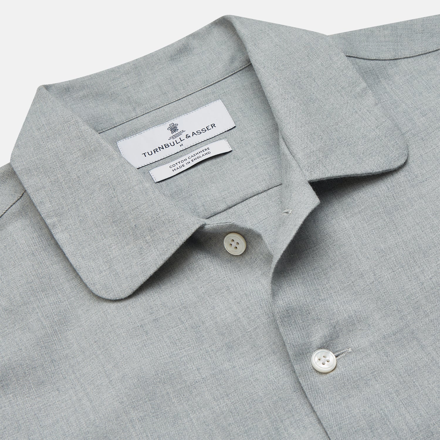 View 3 of product A man stands against a beige background wearing the Turnbull & Asser Cloud Blue Cashmerello Holiday Fit Fellows Shirt, styled with dark trousers, a black belt, and black shoes, looking directly at the camera with a neutral expression.