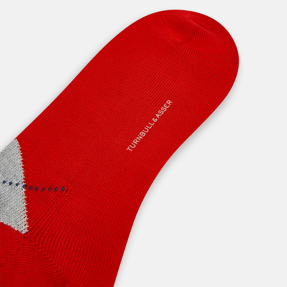 Mid-length orange wool socks by Turnbull & Asser, featuring a classic check pattern in orange, beige, and gray, reminiscent of timeless wool socks, displayed on a plain light background.