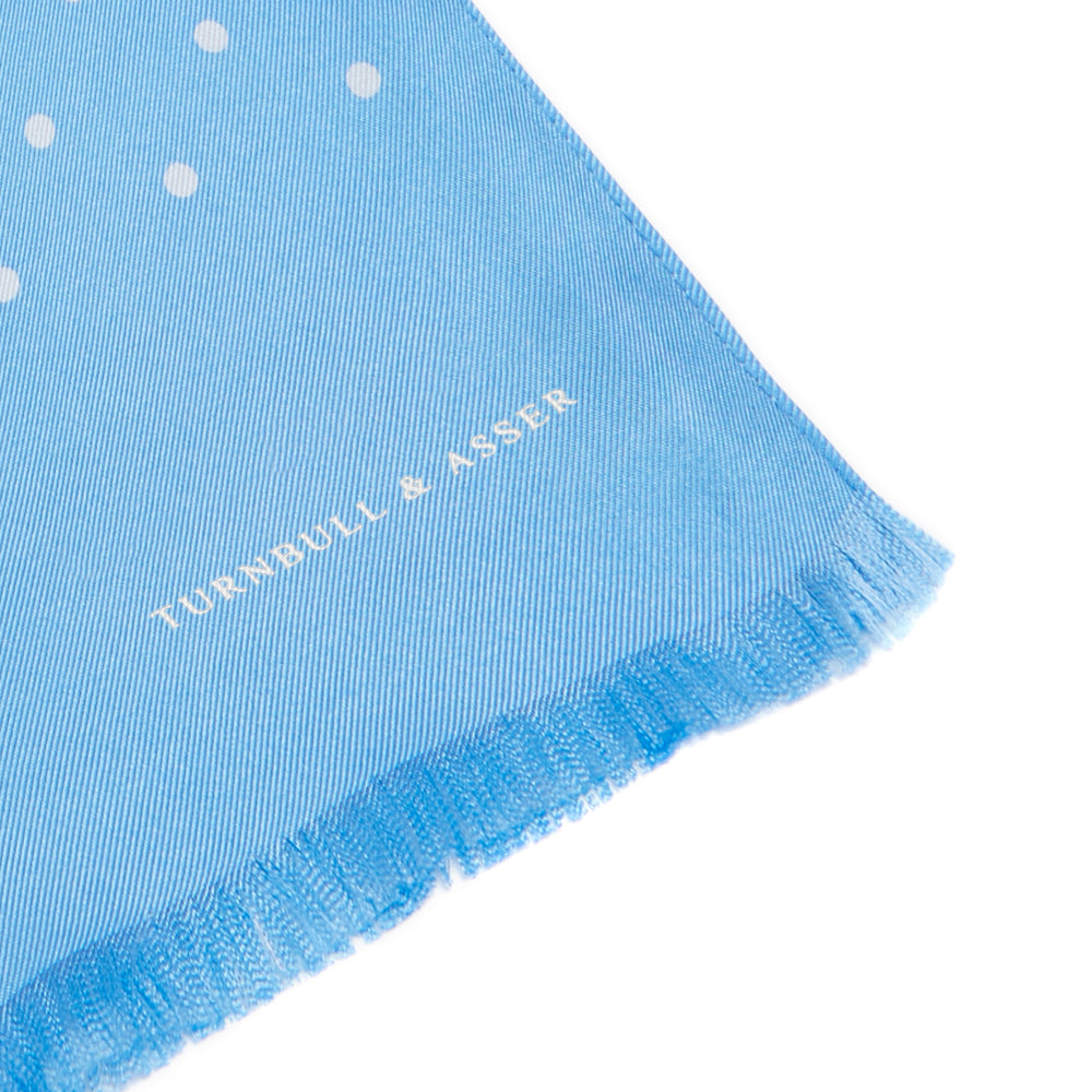 The Turnbull & Asser Azure and White Spotted Silk Scarf features small white polka dots, subtle fringe at the ends, and a delicate hand-printed design, displayed on a plain white background.