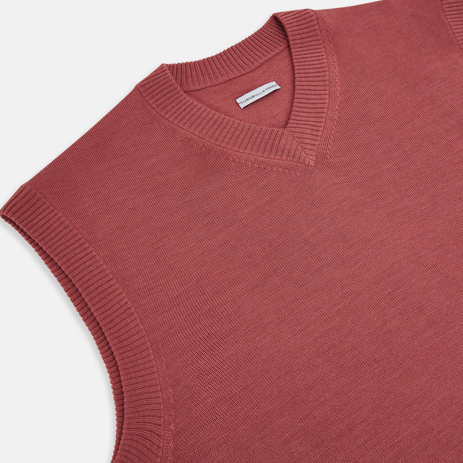 View 2 of product The Turnbull & Asser Antique Pink Fine Merino V-Neck Vest features ribbed trim at the neckline, armholes, and hem—a stylish layering piece for cooler seasons. Shown against a plain white background.