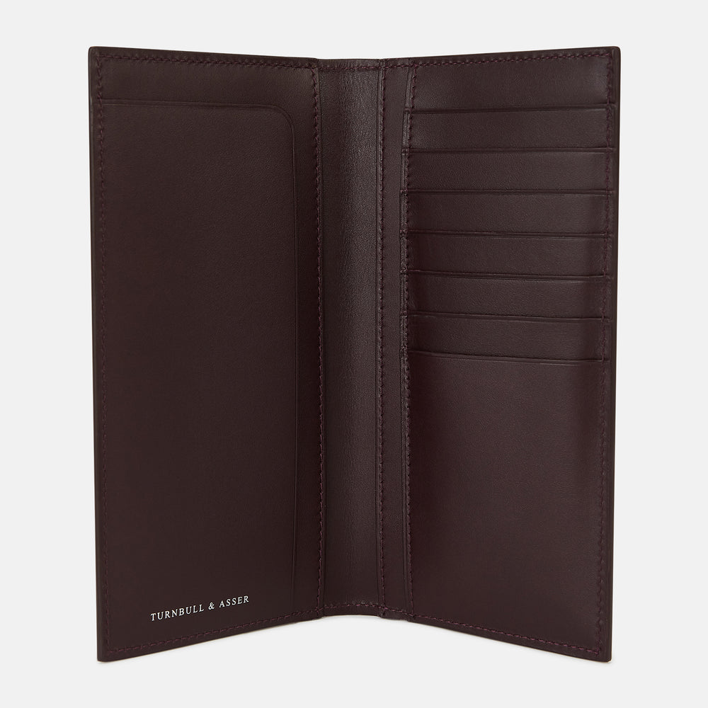 The Turnbull & Asser Burgundy B Cut Continental Wallet, with smooth, unadorned surfaces and visible edge stitching, is pictured closed in rich burgundy Italian leather against a white background.