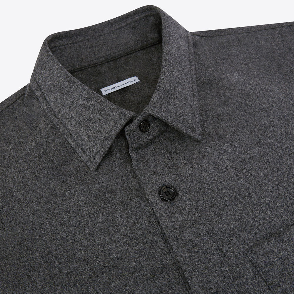 The Grey Highbury Overshirt by Turnbull & Asser is a long-sleeve, button-up charcoal gray overshirt with a single chest pocket, inspired by classic formal jackets and shown laid flat on a white background.