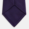 View 4 of product The HOUNDSTOOTH NAVY PLUM TIE by Turnbull & Asser, featuring a textured pattern, is showcased rolled up against a plain white background—an essential accessory.