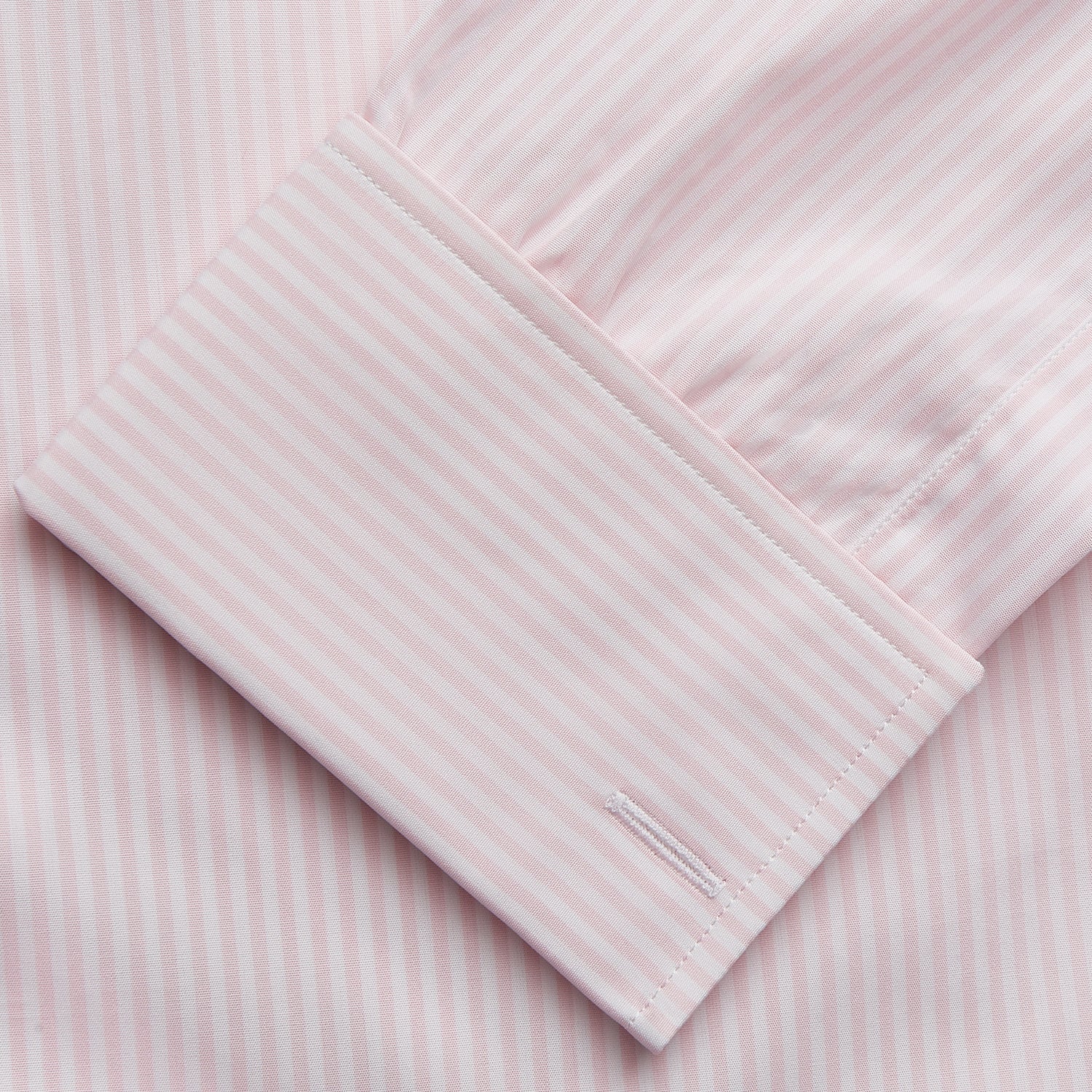 View 3 of product The Turnbull & Asser White and Pink Wide Stripe Shirt with Double Cuffs features a minimalist design, with bold vertical stripes and long sleeves, shown laid flat against a white background.