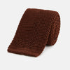 View 1 of product The Turnbull & Asser KNITTED BROWN SILK PLAIN TIE—a stylish, textured accessory—appears rolled up on a white background, perfect for elevating smart outfits.