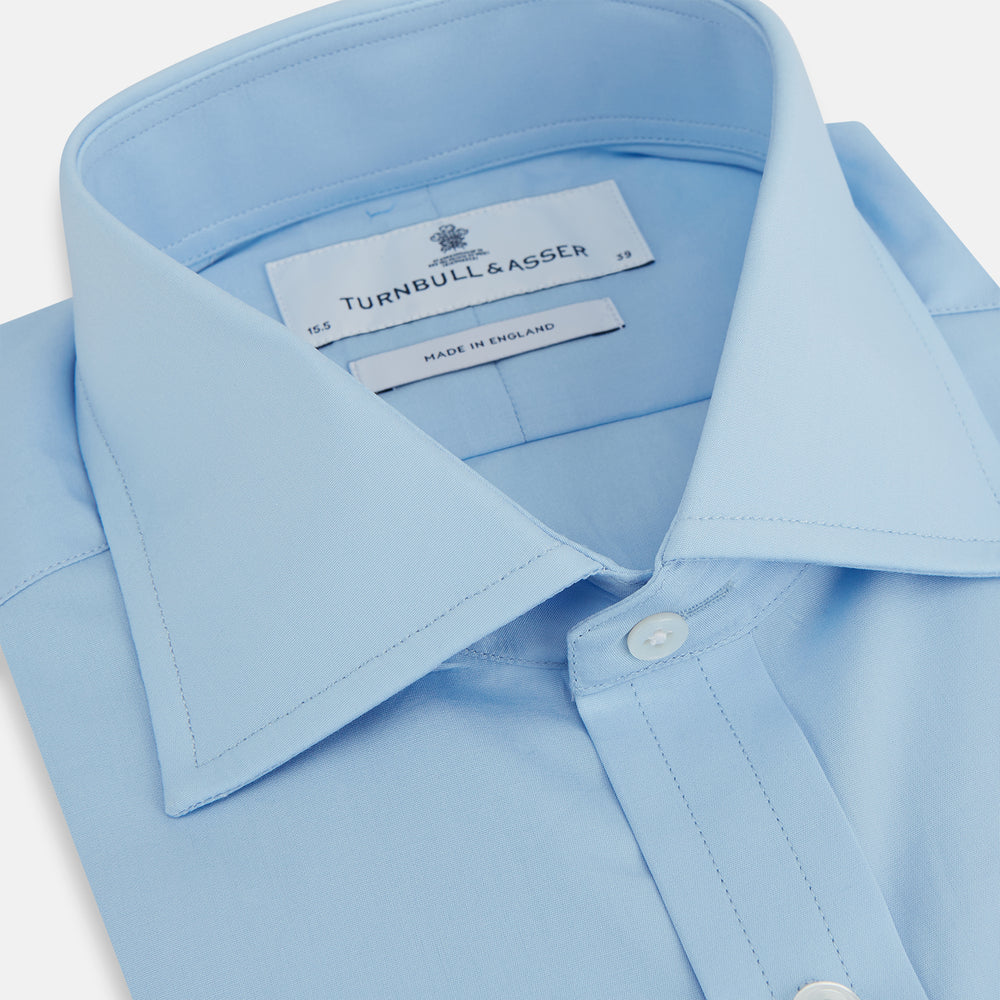 The Turnbull & Asser Dr. No Blue Cotton Shirt with a classic collar, cocktail cuffs, button-up front, and straight hem is featured on a plain white background. As seen on James Bond.