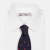 View 2 of product The EMBLEM SPOT NAVY TULIP TIE by Turnbull & Asser features a navy base with red circle motifs, neatly rolled on a white background—an essential accessory for refined style.