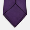 View 4 of product The HORIZONTAL TWILL PLUM TIE by Turnbull & Asser features a solid purple hue and smooth, subtly textured fabric—a versatile accessory to elevate any wardrobe, shown elegantly against a white background.