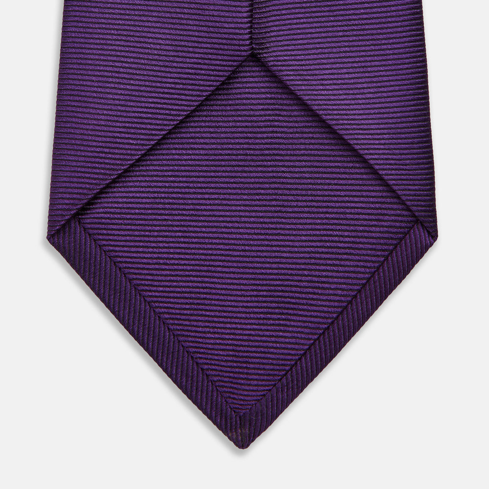 The HORIZONTAL TWILL PLUM TIE by Turnbull & Asser features a solid purple hue and smooth, subtly textured fabric—a versatile accessory to elevate any wardrobe, shown elegantly against a white background.