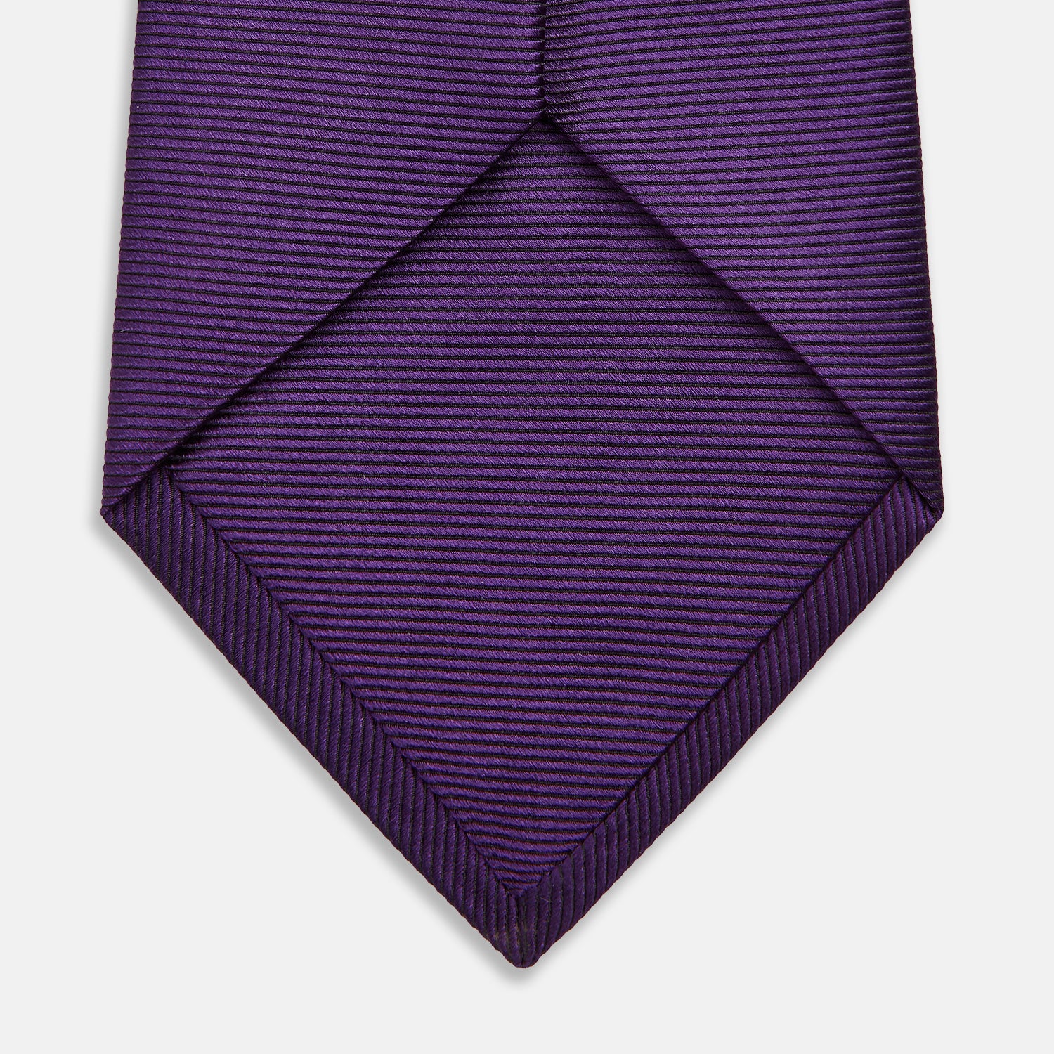 View 4 of product The HORIZONTAL TWILL PLUM TIE by Turnbull & Asser features a solid purple hue and smooth, subtly textured fabric—a versatile accessory to elevate any wardrobe, shown elegantly against a white background.