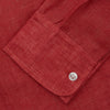 View 5 of product The Turnbull & Asser Plain Red Linen Weekend Fit Shirt with Stand Collar features long sleeves, a button-up front, and two buttoned-flap chest pockets. It is shown neatly laid flat on a plain light background.
