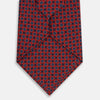 View 3 of product The Turnbull & Asser Red and Blue Geometric Floral Silk Tie features a red background with small blue and white circular floral patterns, exemplifying British craftsmanship.