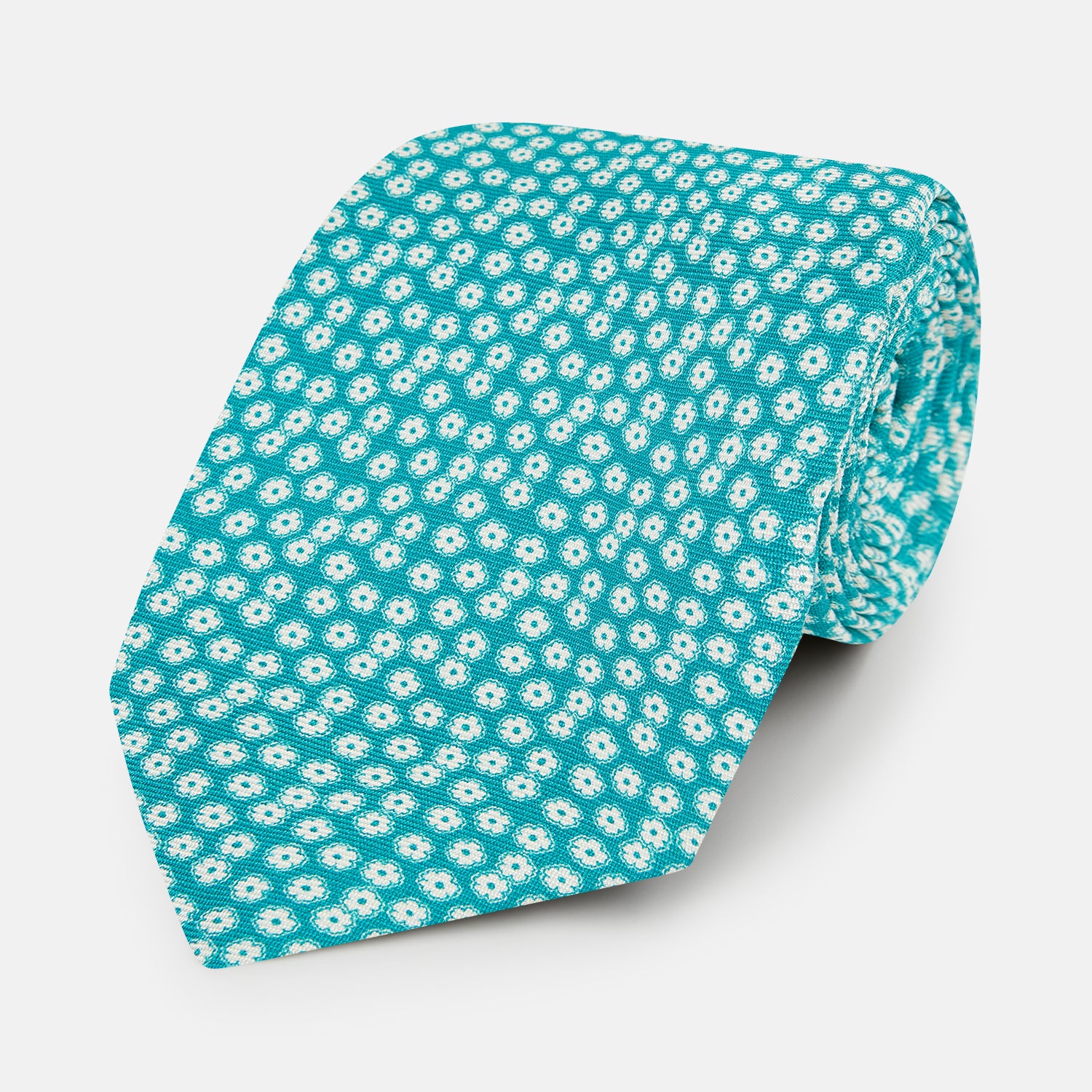 View 1 of product The Turnbull & Asser Turquoise Flower Patterned Silk Tie, featuring small white flowers, is shown rolled up on a white background.