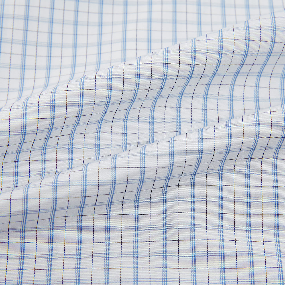 The Turnbull & Asser Sky Blue Combination Graph Check Mayfair Shirt features long sleeves, a pointed collar, buttoned cuffs, and a blue and white check pattern that showcases British craftsmanship. Displayed on a white background.